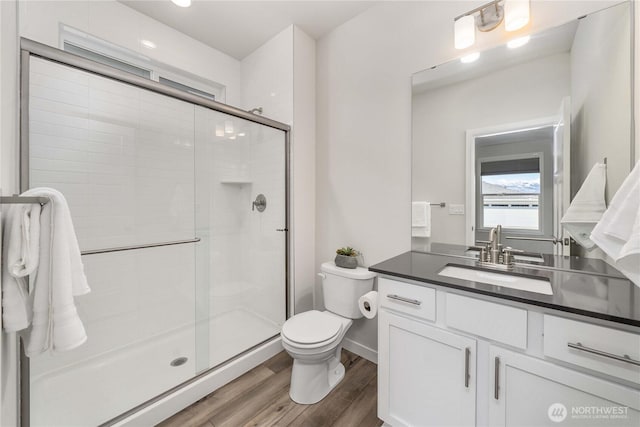full bath featuring vanity, wood finished floors, toilet, baseboards, and a stall shower