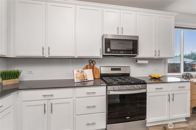 kitchen featuring dark countertops, white cabinets, stainless steel appliances, and tasteful backsplash