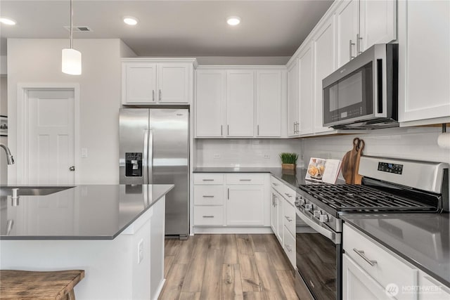 kitchen featuring dark countertops, appliances with stainless steel finishes, light wood-style flooring, and visible vents