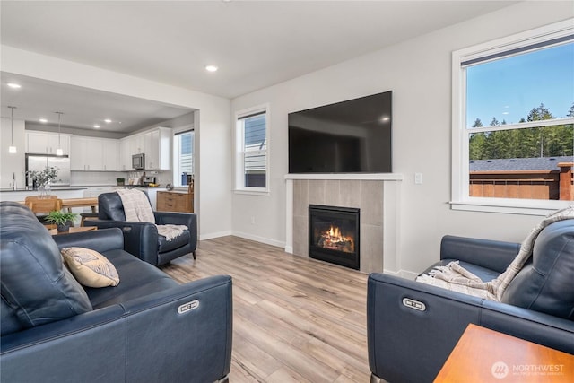living area featuring recessed lighting, light wood finished floors, a wealth of natural light, and a tile fireplace