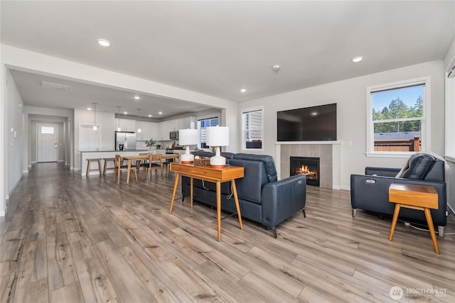 living area featuring light wood-type flooring, recessed lighting, baseboards, and a fireplace
