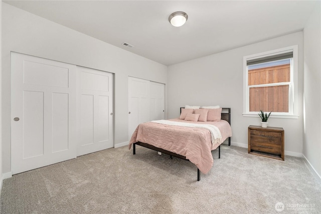 bedroom with multiple closets, baseboards, carpet flooring, and visible vents