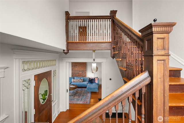 stairway featuring a towering ceiling and wood finished floors
