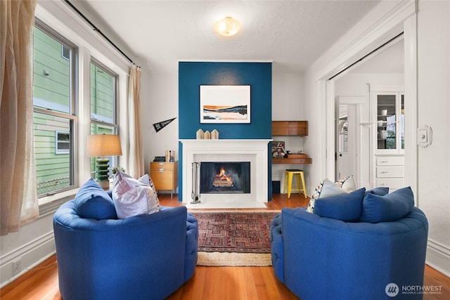 living room with baseboards, a fireplace with flush hearth, and wood finished floors