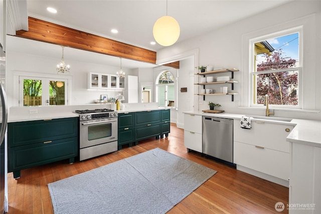 kitchen with green cabinetry, white cabinetry, a chandelier, a sink, and appliances with stainless steel finishes