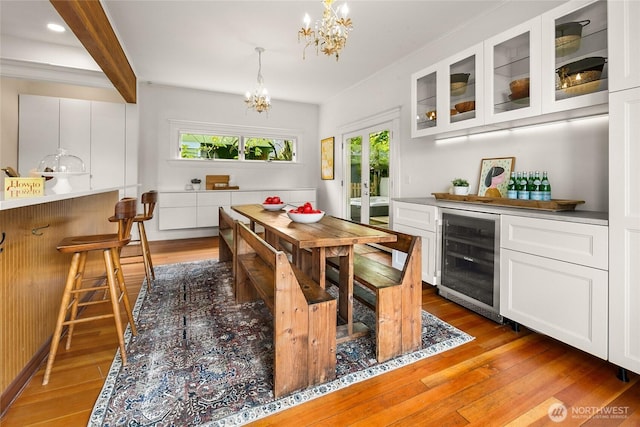 dining space with beverage cooler, light wood-style floors, plenty of natural light, and a chandelier
