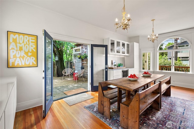 dining space featuring beverage cooler, baseboards, a chandelier, and light wood-style floors