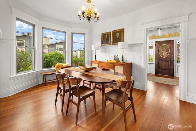 dining area with an inviting chandelier, baseboards, a wealth of natural light, and hardwood / wood-style flooring