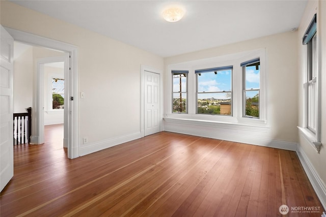 empty room with wood-type flooring and baseboards