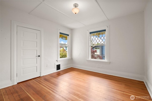 unfurnished room with wood-type flooring, baseboards, and visible vents