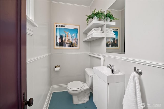 half bathroom featuring crown molding, baseboards, toilet, and vanity