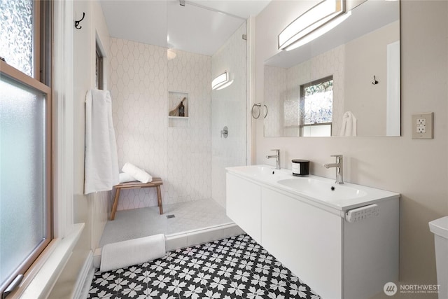 full bathroom with double vanity, a walk in shower, tile patterned floors, and a sink