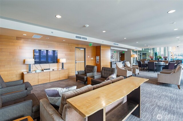 carpeted living area with wooden walls, recessed lighting, and visible vents