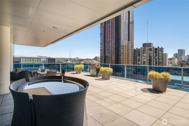 view of patio featuring a view of city, a grill, and a balcony