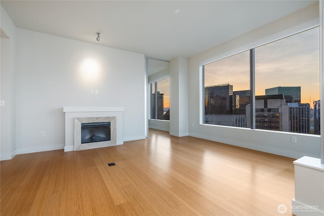 unfurnished living room featuring baseboards, wood finished floors, and a fireplace