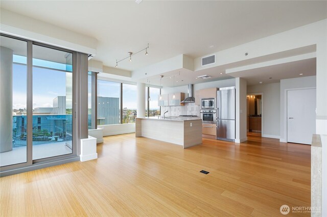 unfurnished living room featuring visible vents, a sink, and light wood-type flooring
