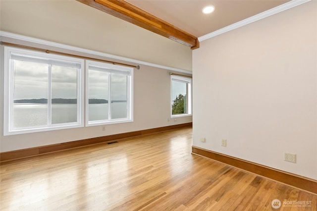empty room with crown molding, beam ceiling, light wood-style flooring, baseboards, and visible vents