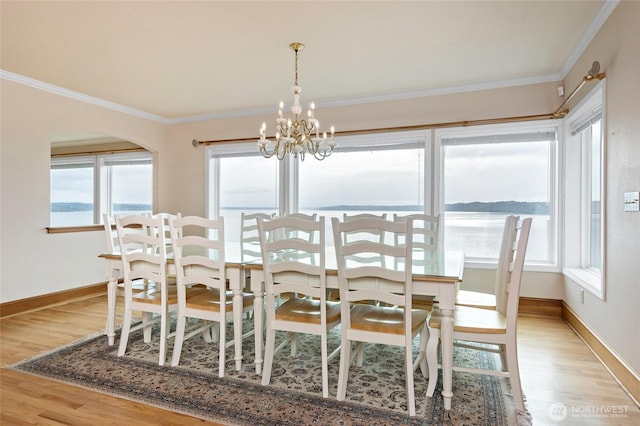 dining room featuring baseboards, ornamental molding, light wood-style flooring, and a notable chandelier