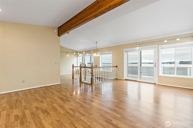 spare room featuring baseboards, lofted ceiling with beams, and wood finished floors
