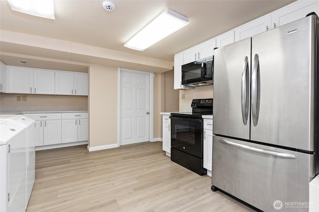 kitchen with black appliances, white cabinetry, light wood-style flooring, and washer and clothes dryer