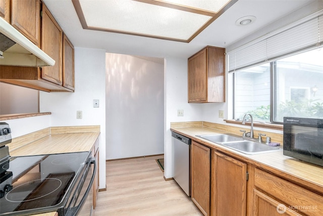 kitchen featuring light countertops, a sink, under cabinet range hood, and stainless steel appliances