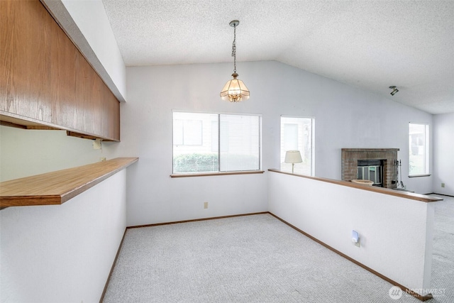 kitchen with vaulted ceiling, hanging light fixtures, a fireplace, and carpet flooring