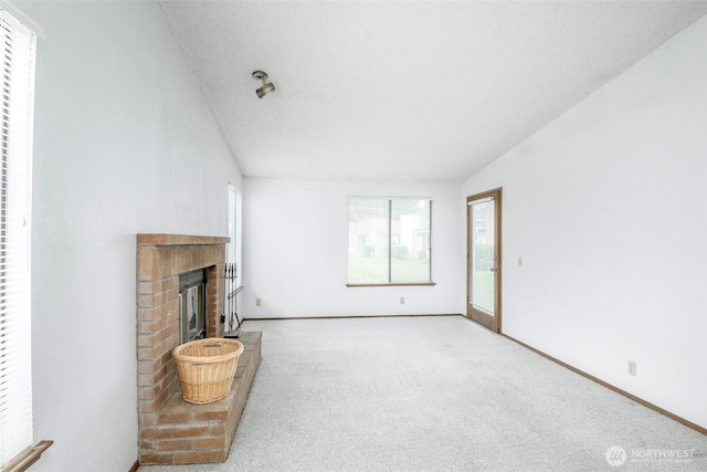 unfurnished living room featuring baseboards, carpet flooring, lofted ceiling, and a fireplace