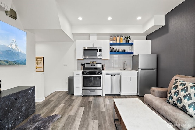 kitchen featuring dark wood-style flooring, a sink, light countertops, stainless steel appliances, and white cabinetry