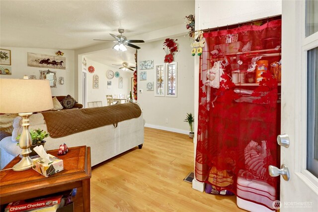 living area with wood finished floors and a ceiling fan