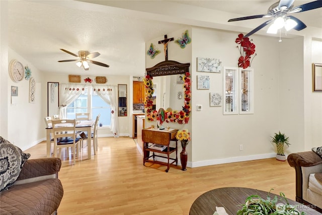 living room featuring a ceiling fan, light wood-type flooring, and baseboards