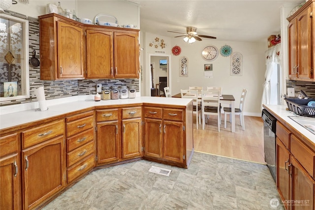 kitchen featuring a ceiling fan, dishwashing machine, a peninsula, brown cabinets, and tasteful backsplash