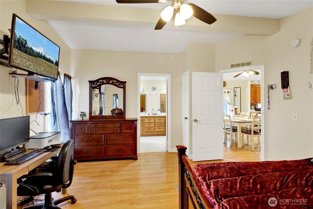 bedroom featuring light wood-type flooring, beam ceiling, a desk, ensuite bathroom, and ceiling fan