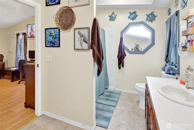 bathroom featuring vanity, baseboards, toilet, and vaulted ceiling