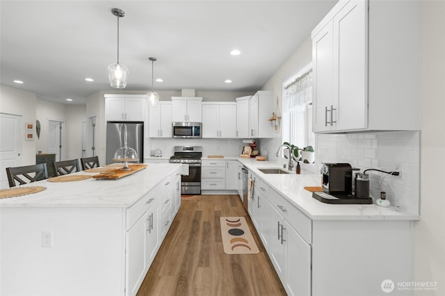 802 SE Cody St, Rainier, WA 98576 - kitchen featuring appliances with stainless steel finishes, a sink, a kitchen island, light wood-style flooring, and white cabinetry