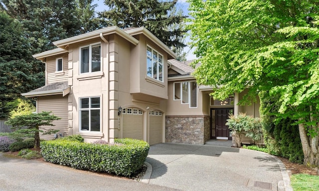view of front of home featuring roof with shingles, an attached garage, driveway, and stone siding