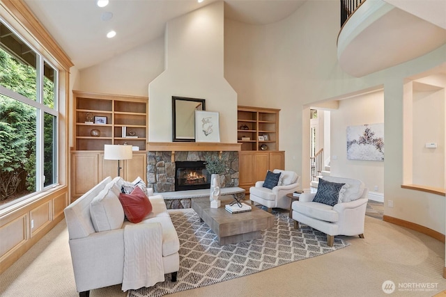 carpeted living room featuring a stone fireplace, recessed lighting, baseboards, and high vaulted ceiling