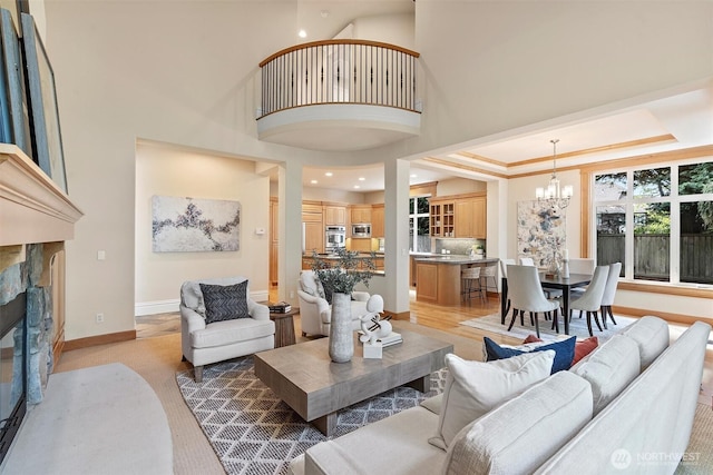 living area featuring a stone fireplace, baseboards, and a chandelier