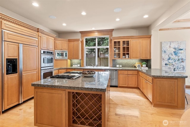 kitchen featuring light wood-style floors, built in appliances, tasteful backsplash, and a peninsula