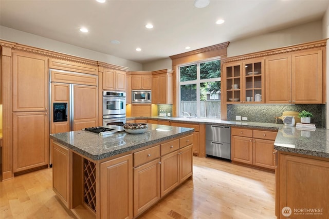 kitchen featuring light wood-style flooring, appliances with stainless steel finishes, backsplash, and a kitchen island
