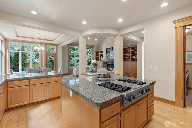 kitchen featuring a glass covered fireplace, a notable chandelier, stainless steel gas stovetop, recessed lighting, and light wood-style flooring