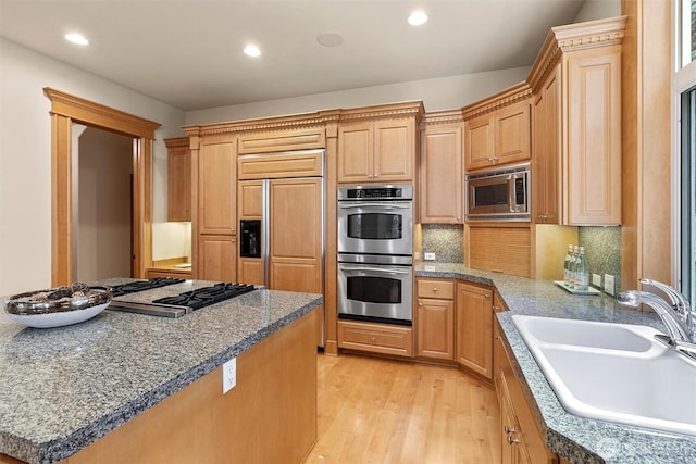 kitchen with tasteful backsplash, a sink, light wood-style floors, built in appliances, and recessed lighting