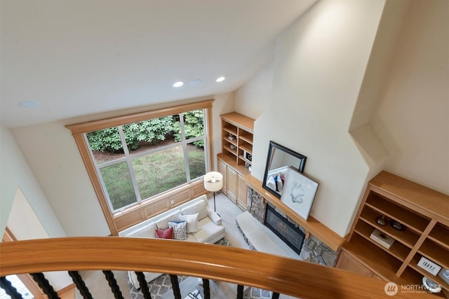 living area with vaulted ceiling, recessed lighting, and a stone fireplace