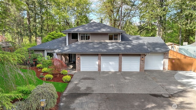 view of front of home with roof with shingles, fence, brick siding, a chimney, and concrete driveway