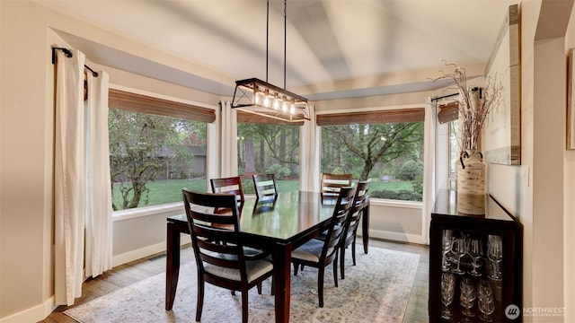 dining space featuring baseboards, wood finished floors, and vaulted ceiling