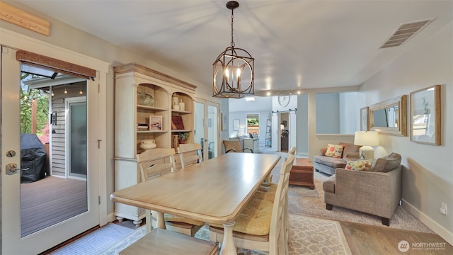 dining area with baseboards, wood finished floors, a chandelier, and visible vents