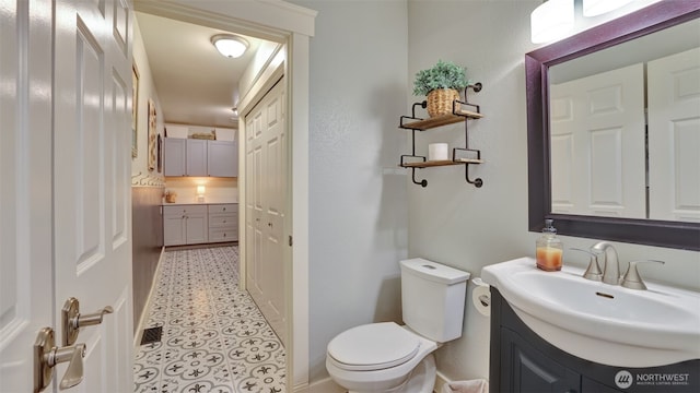 bathroom with vanity, baseboards, tile patterned floors, and toilet