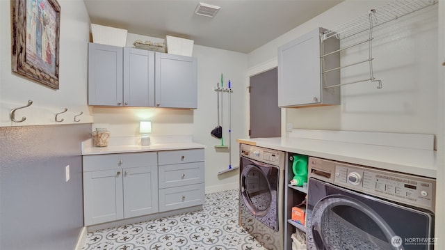 washroom with baseboards, visible vents, cabinet space, and washing machine and clothes dryer