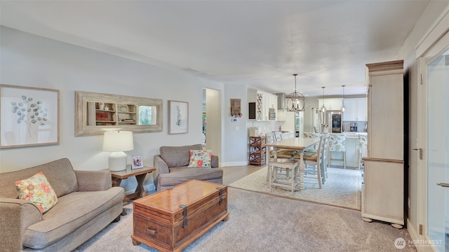living room featuring light colored carpet, plenty of natural light, a chandelier, and visible vents