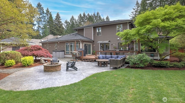 rear view of property with a lawn, an outdoor living space with a fire pit, a patio, and a deck
