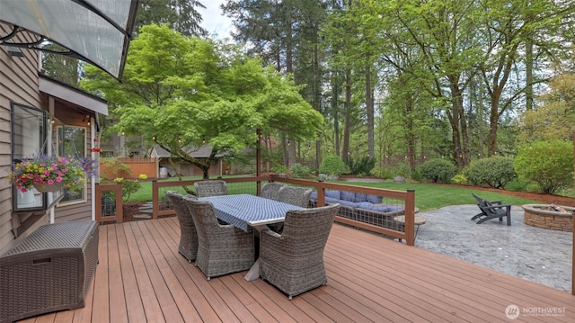 wooden deck with outdoor dining space, a fire pit, fence private yard, and a patio